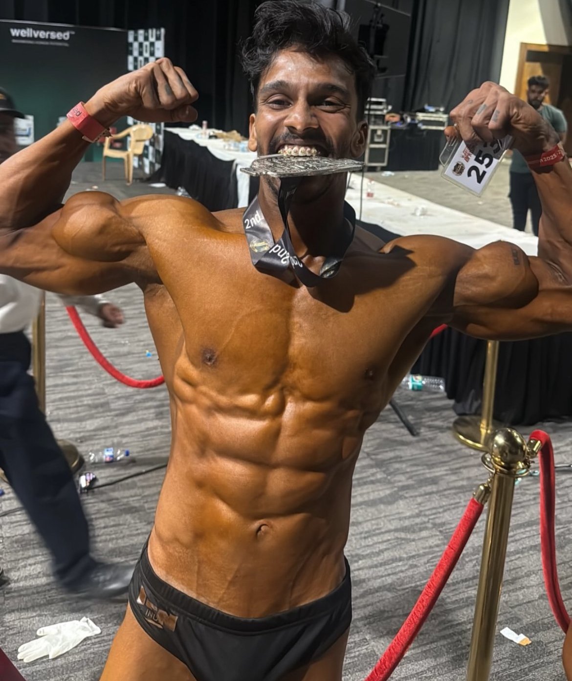 Loki ICN competition double bicep pose with silver medal